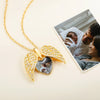 Un collar personalizado con foto en forma de corazón yace junto a una foto impresa de una pareja sonriente con su bebé. El dije está adornado con pequeñas piedras brillantes y guarda una imagen en su interior.