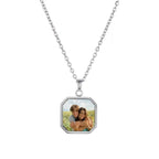El Collar personalizado con foto secreta, color plateado, captura momentos únicos: dos personas sonriendo y abrazándose al aire libre bajo un cielo azul. Es un regalo personalizado y original.
