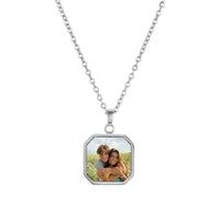 El Collar personalizado con foto secreta, color plateado, captura momentos únicos: dos personas sonriendo y abrazándose al aire libre bajo un cielo azul. Es un regalo personalizado y original.