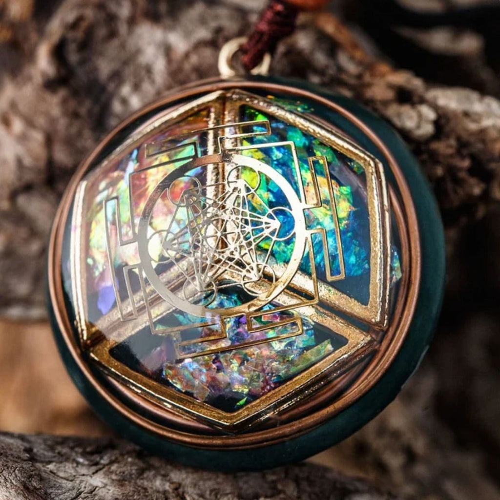 Primer plano del collar Talismán energético con geometría sagrada, que presenta un fondo iridiscente de colores, motivos geométricos como un hexágono, diseños de alambre metálico y se exhibe sobre una superficie natural texturizada.