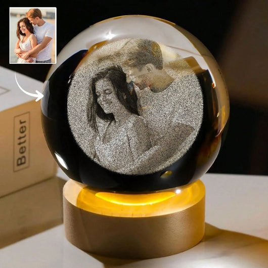 La Esfera de Cristal de los Recuerdos muestra a una pareja sonriente, su foto grabada en cristal sobre una base de madera, recreada a partir de la imagen original y señalada por una flecha como un regalo personalizado único.