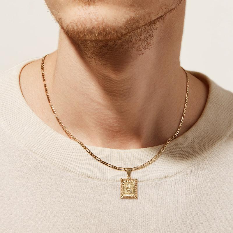 Una persona lleva un jersey de color crema y dos cadenas de oro, una de las cuales es el "Collar Marco con inicial personalizada (Oferta 2x1)" con un colgante rectangular grabado. Sólo se le ve la mitad inferior de la cara y el cuello.