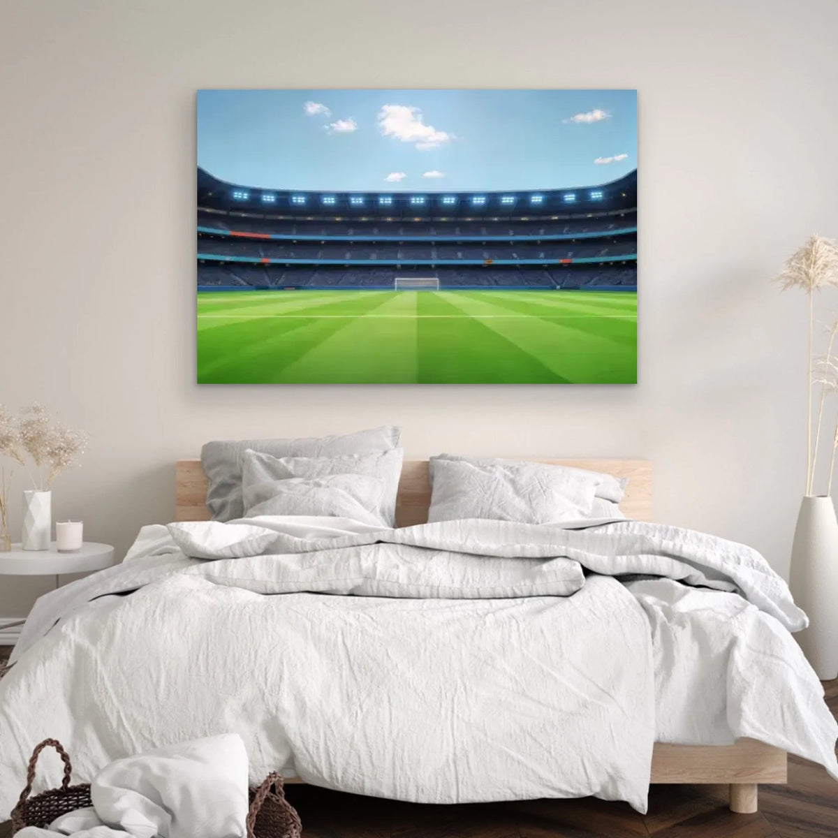 Un acogedor dormitorio con una cama bien hecha y ropa de cama blanca luce el lienzo personalizado "El equipo soñado de papá - Fútbol" encima del cabecero, con una escena de un estadio de fútbol. Las plantas secas añaden un toque decorativo a la habitación.