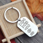 El Llavero Familia personalizable es de acero inoxidable con una placa metálica grabada por láser que muestra figuras de dos adultos, dos niños y un perro, junto a los nombres George, Amanda, Ben, Lucy y Rufus.