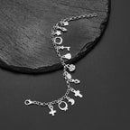 La Pulsera con 13 amuletos (2x1 limitado) incluye corazones, estrellas, una cruz, una llave y una luna creciente en plata 925 sobre una superficie de piedra negra texturizada, ideal para atraer energía positiva a tu vida diaria.