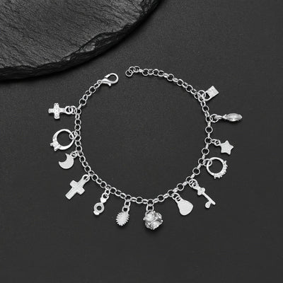 Pulsera con 13 amuletos (2x1 limitado) de plata 925: cruz, luna, corazón, cactus y más; desborda energía positiva. Exhibida sobre fondo negro junto a una piedra texturizada.