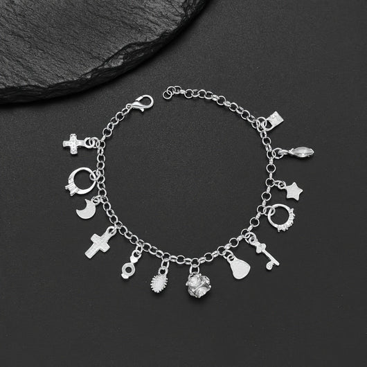 Pulsera con 13 amuletos (2x1 limitado) de plata 925: cruz, luna, corazón, cactus y más; desborda energía positiva. Exhibida sobre fondo negro junto a una piedra texturizada.