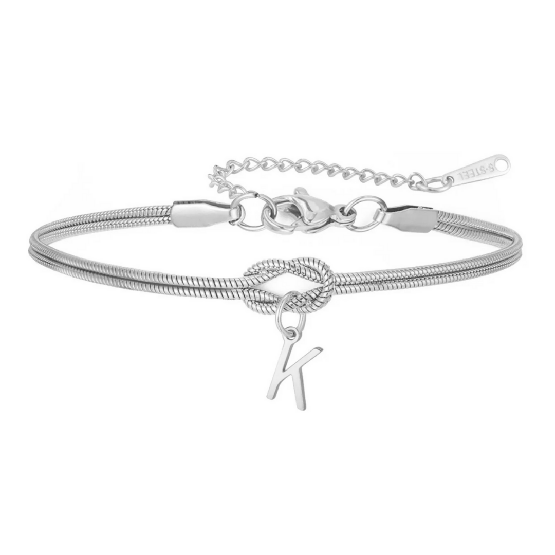 Pulsera de nudo con inicial: elegante cadena plateada con detalle de nudo central y dije colgante letra K. Incluye broche ajustable y extensión. Ideal como regalo inolvidable.