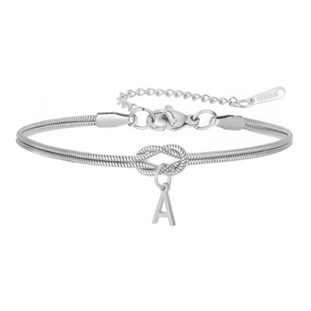 La Pulsera de nudo con inicial es una pulsera de plata con detalle de nudo y dije de letra A colgante. Cuenta con una cadena ajustable y cierre de langosta, un regalo inolvidable para cualquier ocasión.
