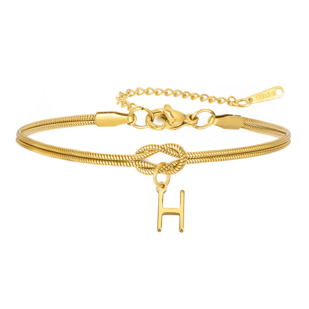 Pulsera de nudo con inicial: una pulsera personalizada tipo cadena de serpiente dorada, con detalle de nudo, dije colgante letra H y broche ajustable con extensión. Un regalo inolvidable.