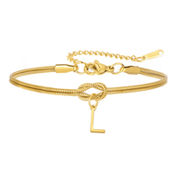 La Pulsera de nudo con inicial es dorada, tiene una fina cadena tipo serpiente, un nudo central y un dije colgante con la letra "L". Incluye extensión ajustable y placa "STEEL", ideal como regalo inolvidable y pulsera personalizada.