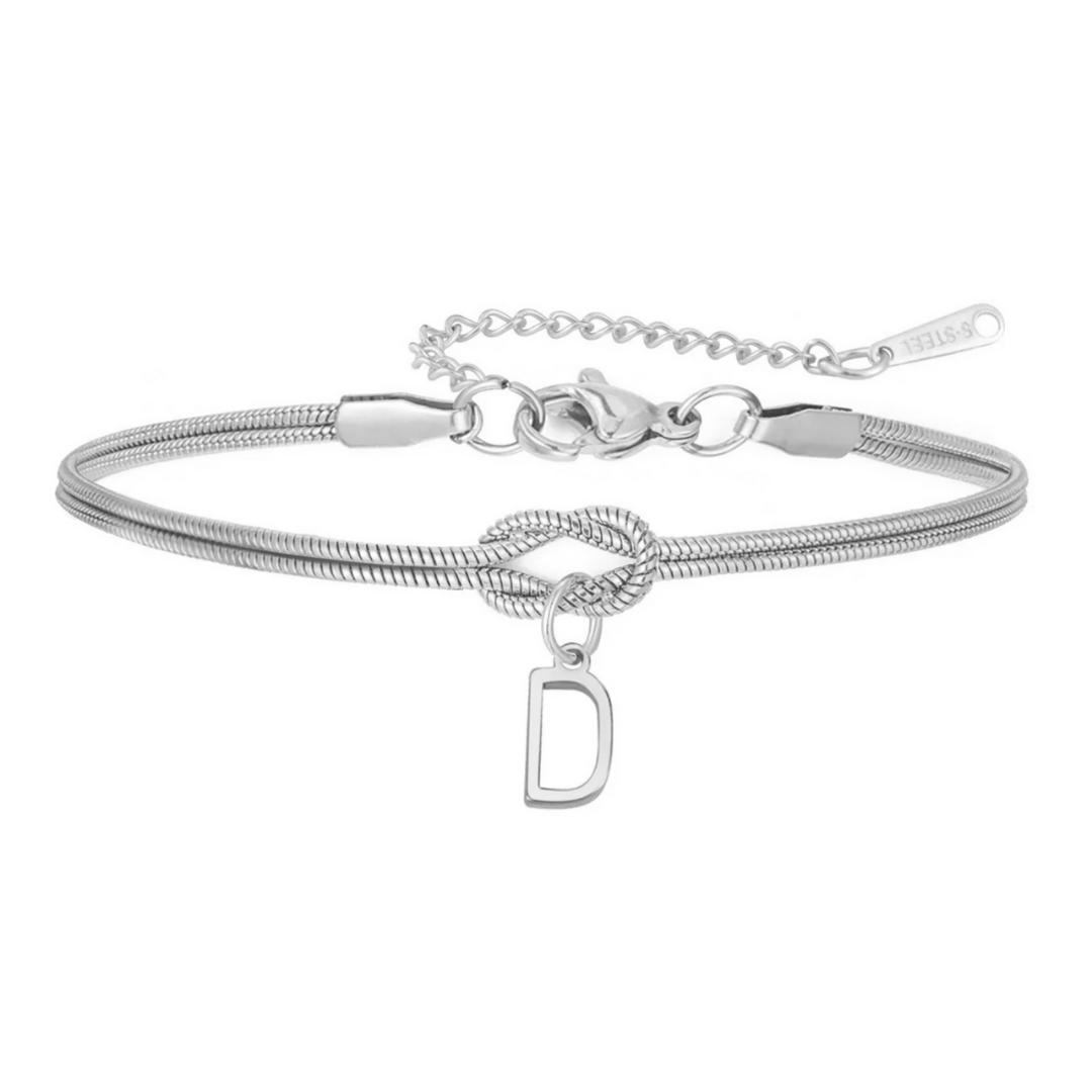La Pulsera de nudo con inicial es una delicada pulsera plateada con cadena tipo serpiente, nudo central y dije colgante letra D. Su cadena ajustable y broche langosta la hacen el regalo personalizado perfecto.