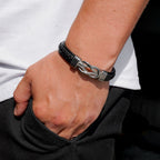 Una persona con camisa blanca y pantalón negro tiene la mano en el bolsillo, mostrando la Pulsera con nudo infinito personalizable - A mi hijo, un regalo ideal para un hijo.