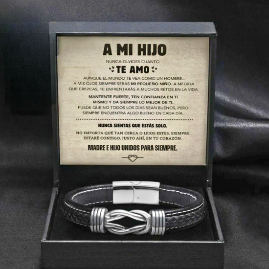 Una caja de regalo negra muestra la "Pulsera con nudo infinito - A mi hijo", una pulsera de cuero negro y plateado con un cariñoso mensaje en español de mamá a hijo sobre el amor y la unidad impreso en el interior de la tapa. Perfecto regalo para hijo.