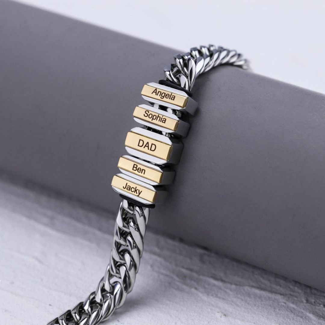 La Pulsera de cadena personalizada es una pulsera plateada con cinco cuentas rectangulares grabadas con nombres (Angela, Sophia, DAD, Ben y Jacky) y detalles en dorado que la hacen un regalo elegante para papá.