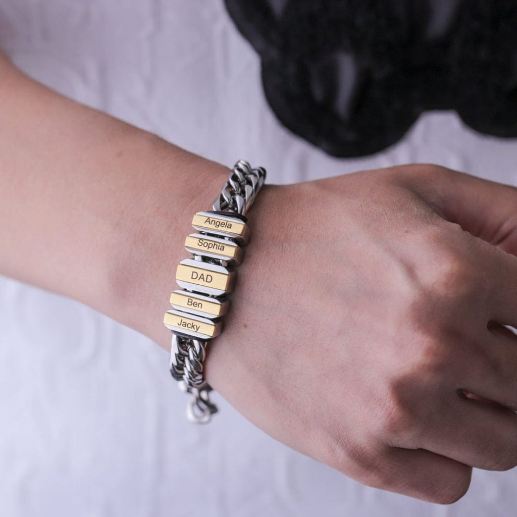 Una persona con atuendo blanco y negro ilumina la Pulsera de cadena personalizada plateada con dijes dorados que dicen Angela, Sophia, DAD, Ben y Jacky: un regalo ideal para padres.