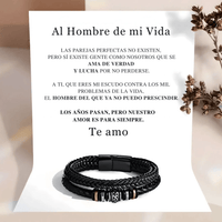Detrás de la Pulsera de cuero - Al hombre de mi vida, con detalles metálicos, hay una nota con un romántico mensaje en español. Las flores secas marrones de la derecha añaden un toque cálido a este regalo de amor.