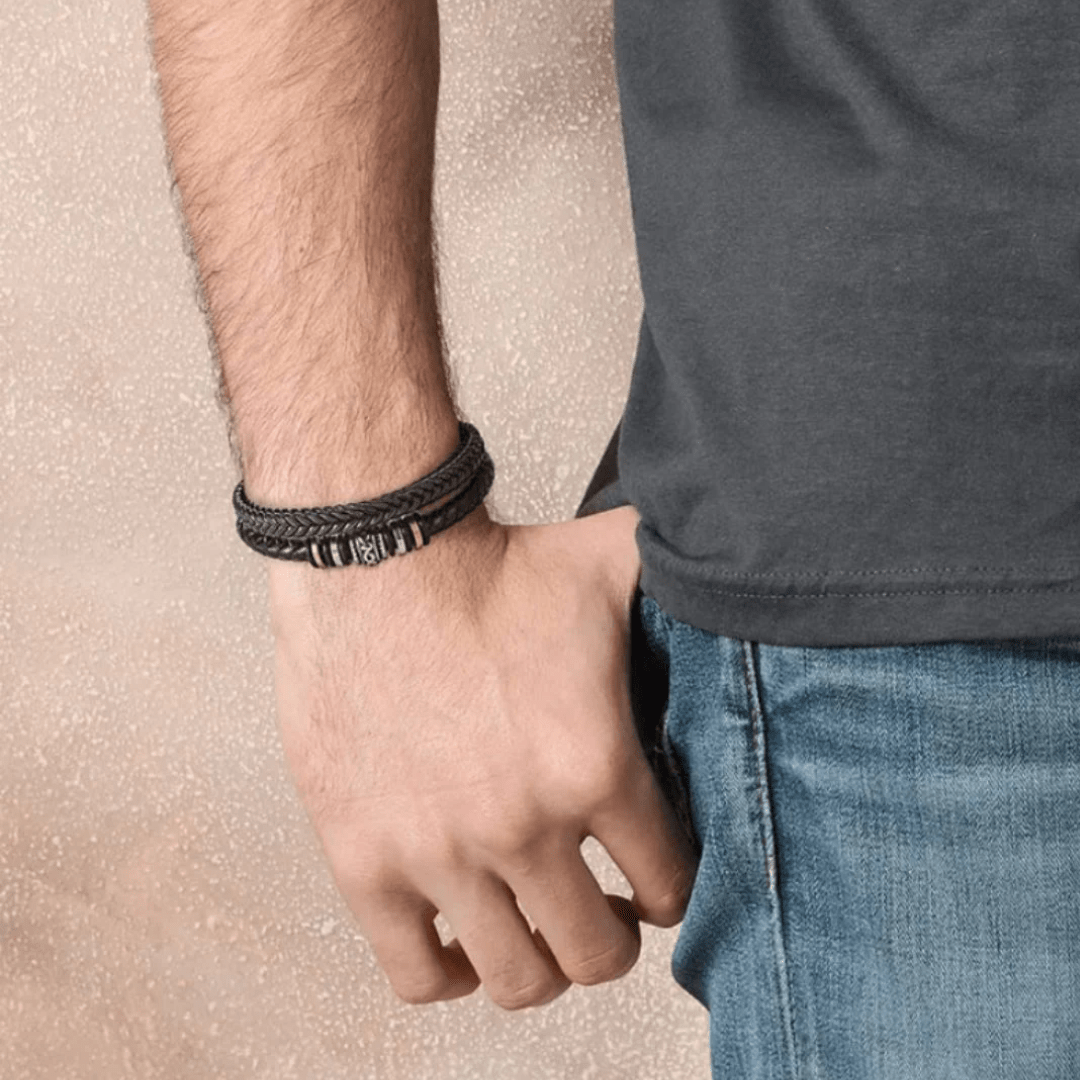 Un hombre con camiseta oscura y jeans azules luce en la muñeca la Pulsera de cuero - Al hombre de mi vida, ideal como regalo especial o pulsera personalizada.