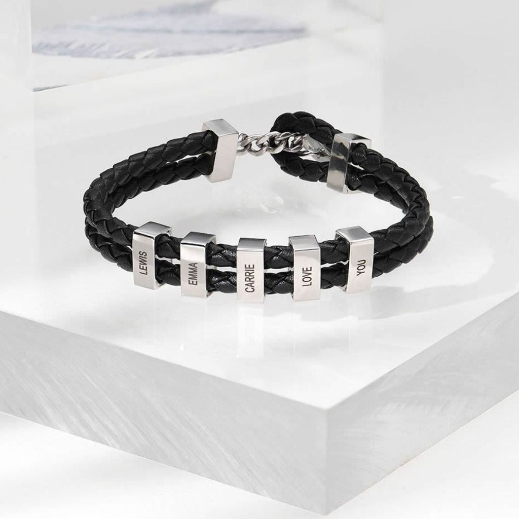 La Pulsera de cuero para Papá en color negro cuenta con seis cuentas rectangulares plateadas grabadas con los nombres LEWIS, EMMA, CARRIE, I, LOVE y YOU. Es el regalo perfecto para hombre.