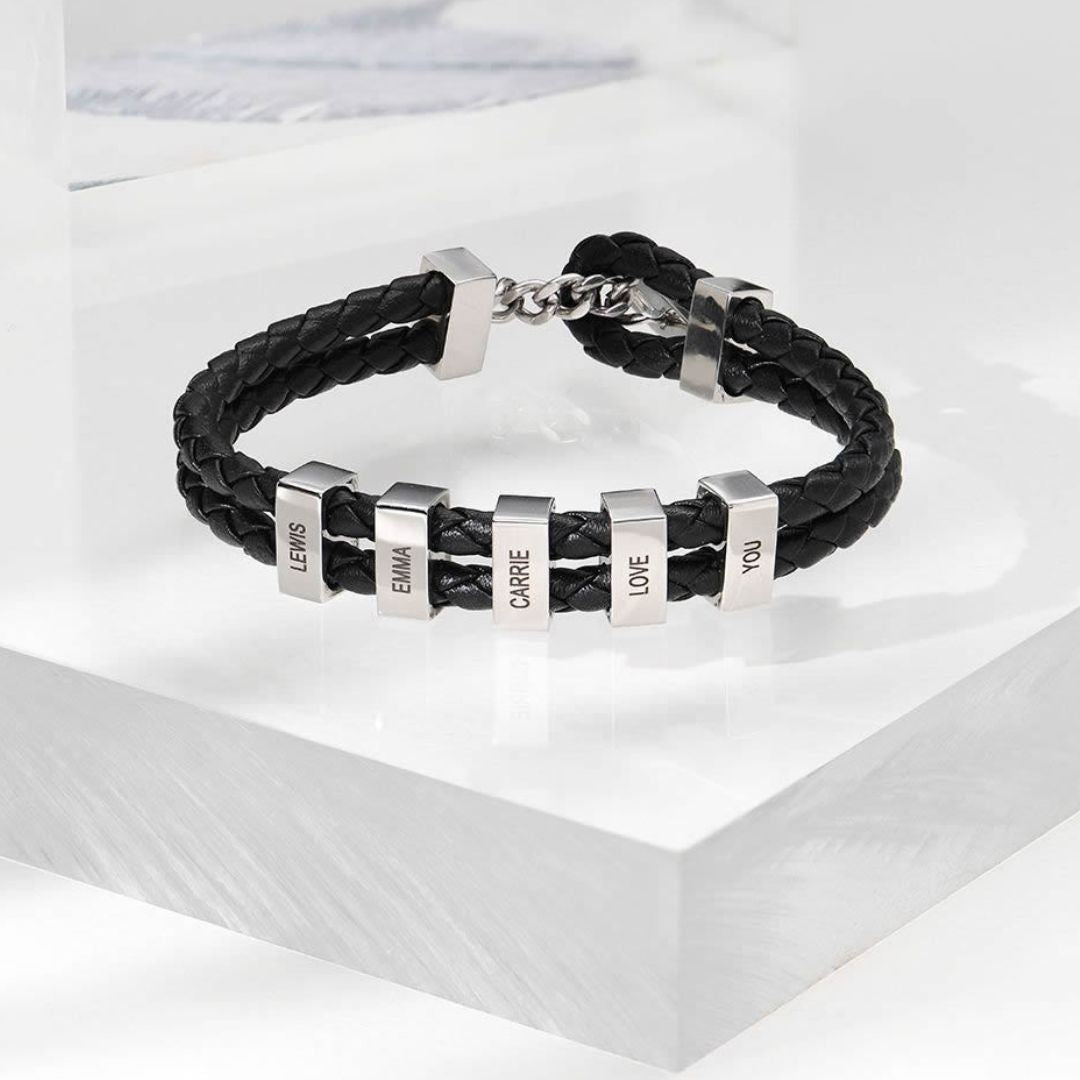 La Pulsera de cuero para Papá en color negro cuenta con seis cuentas rectangulares plateadas grabadas con los nombres LEWIS, EMMA, CARRIE, I, LOVE y YOU. Es el regalo perfecto para hombre.