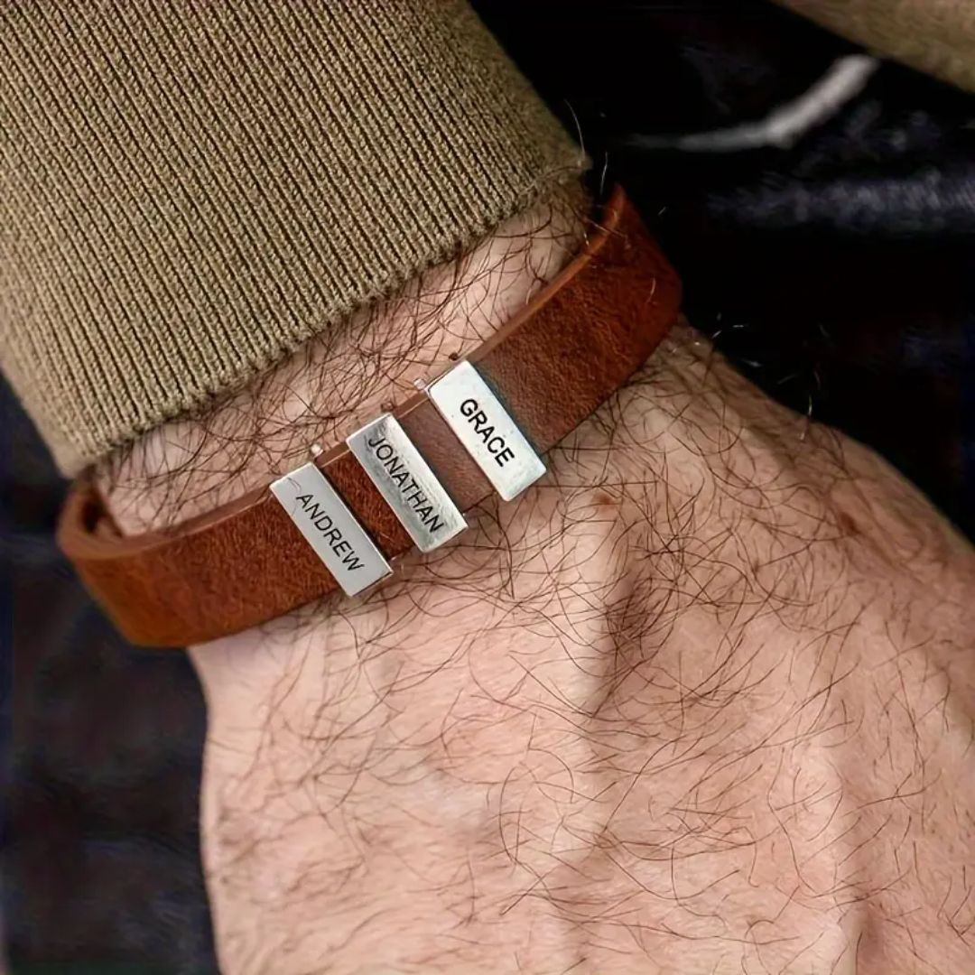 Primer plano de una muñeca con una Pulsera de hombre con nombres grabados que incluye tres cuentas rectangulares de plata grabadas con los nombres Andrew, Jonathan y Grace. Se lleva con un jersey marrón de manga larga, un regalo original ideal para hombre.