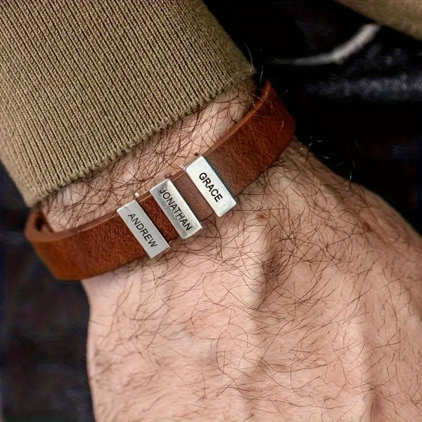 Primer plano de una muñeca con una Pulsera de hombre con nombres grabados que incluye tres cuentas rectangulares de plata grabadas con los nombres Andrew, Jonathan y Grace. Se lleva con un jersey marrón de manga larga, un regalo original ideal para hombre.
