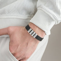 Una persona vestida con ropa de color claro tiene la mano en el bolsillo, mostrando una Pulsera de hombre con nombres grabados con cuatro etiquetas blancas-JACKSON, MASON, HENRY, y MADISON-un regalo ideal original hombre.