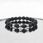 A Pulsera de piedra volcánica personalizada, con cuentas negras que simulan roca volcánica y letras plateadas formando una palabra, ideal como pulsera personalizada para papá o un regalo especial para el Día del Padre.