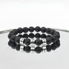 A Pulsera de piedra volcánica personalizada, con cuentas negras que simulan roca volcánica y letras plateadas formando una palabra, ideal como pulsera personalizada para papá o un regalo especial para el Día del Padre.