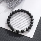 La Pulsera de piedra volcánica personalizada, con cuentas negras y cuatro separadores plateados, luce un diseño poroso tipo lava; es el regalo perfecto para papá y una pulsera especial para el Día del Padre.
