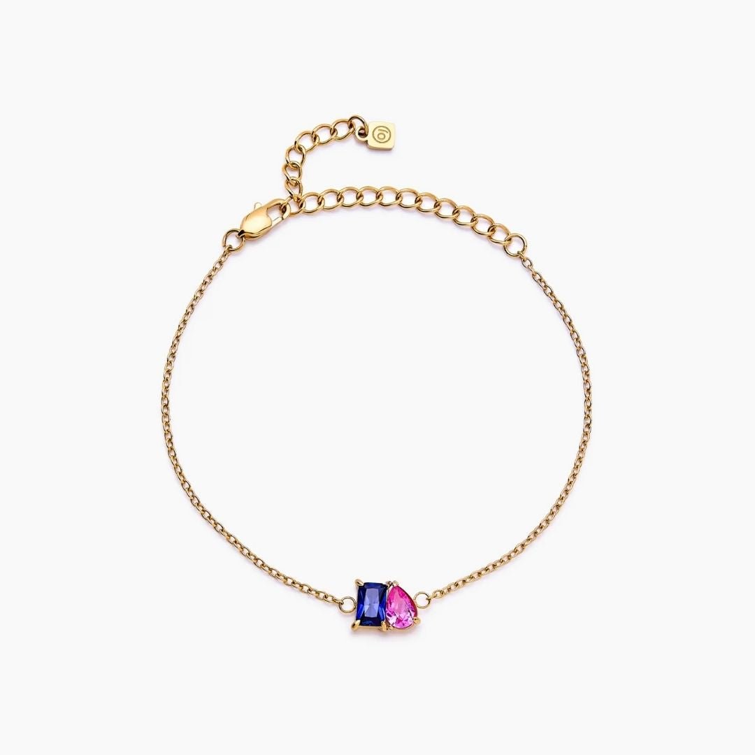 Pulsera dos mitades con piedras de nacimiento en color dorado, ajustable, con un rectángulo azul y una lágrima rosa al centro. Esta joya personalizada es ideal como pulsera de piedras de nacimiento y destaca sobre fondo blanco.