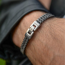 Cargar imagen en el visor de la galería, Un primer plano de una muñeca con la pulsera grabada - A mi amor, de cadena tejida plateada y broches personalizados con &quot;Jackson&quot;, &quot;Daddy&quot; y un corazón. Un regalo masculino, ideal para quien lleva chaqueta de cuero negra.