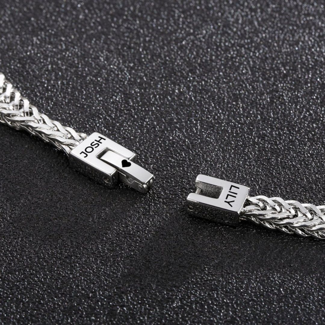 Un primer plano de la Pulsera grabada - A mi amor, una pulsera de plata personalizada con cierres etiquetados JOSH y LILY, desplegada sobre negro texturizado-un regalo ideal para hombre.
