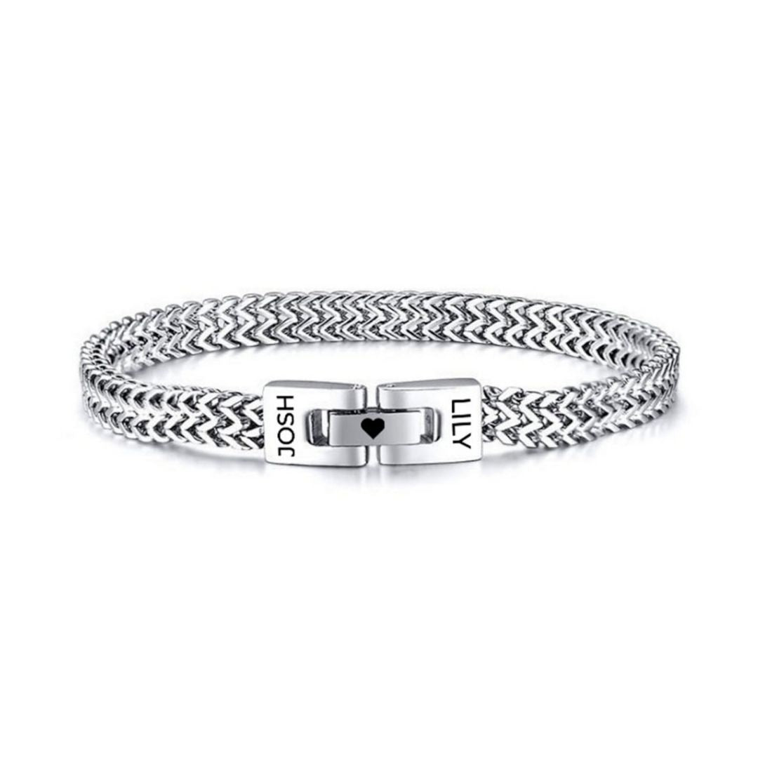 Pulsera grabada - A mi amor: pulsera plateada trenzada con cierre y nombres "JOSH" y "LILY" grabados, separados por un pequeño corazón. Un regalo ideal para hombre.