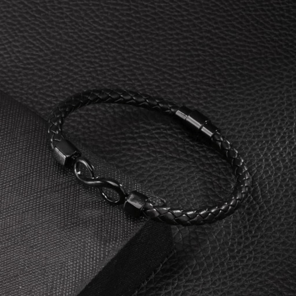 La Pulsera Infinito - A mi hijo es una pulsera de cuero trenzado negro con un elegante cierre infinito de metal negro, que se muestra sobre una superficie negra texturizada: un regalo elegante para su hijo.