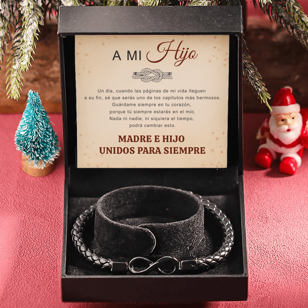 La Pulsera Infinito - A mi hijo es una pulsera de cuero trenzado negro con un charm infinito, presentada en un estuche de regalo. En su interior figura el mensaje en español "Madre e hijo unidos para siempre". Incluye una festiva figurita de Papá Noel-el regalo perfecto para hijo.