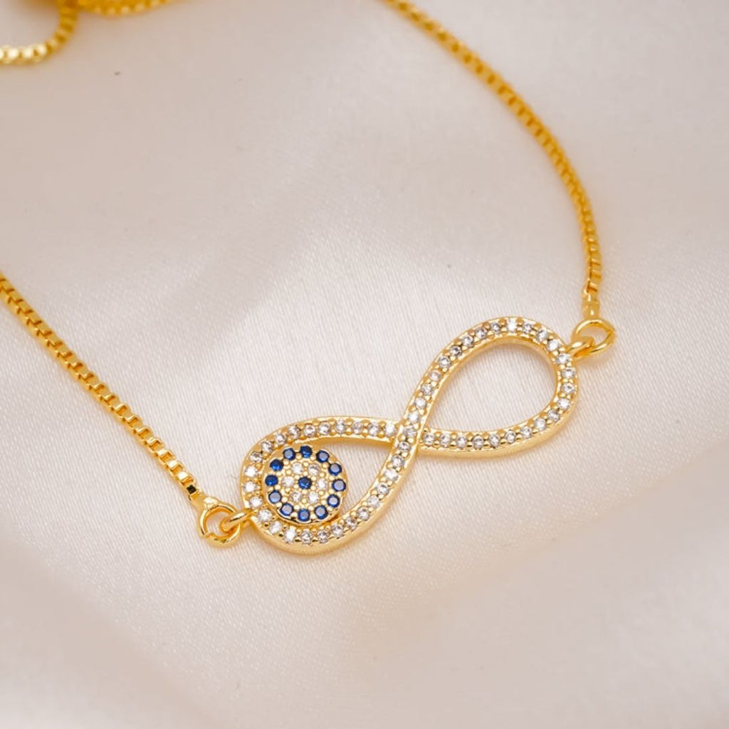 La Pulsera Infinito con ojo turco (OFERTA 2X1) presenta un símbolo de infinito con piedras brillantes y un círculo de piedras azules y claras que se asemeja al ojo turco, como protección contra la energía negativa. Se presenta en un tejido suave y pálido.