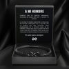 La Pulsera Infinito personalizada - A mi Hombre, una pulsera trenzada negra, se presenta en una caja de regalo negra abierta. Dentro de la tapa hay un sincero mensaje en español titulado 