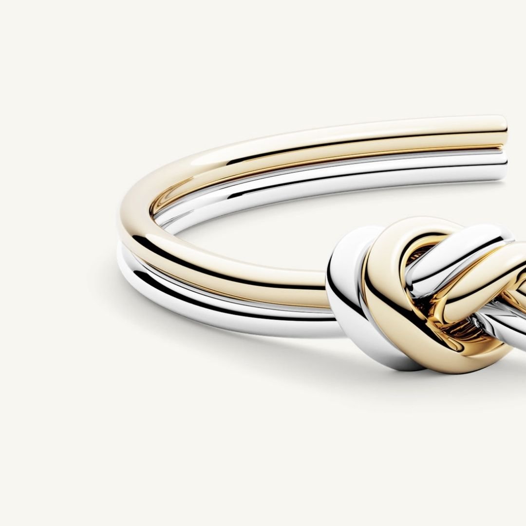 Un primer plano de la Pulsera Nudo infinito dual, una pulsera unisex con bandas de oro y plata entrelazadas en un diseño de nudo, fabricada en acero inoxidable, perfecta como regalo de aniversario.