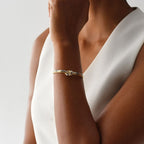 Una persona con un top blanco sin mangas luce la Pulsera Nudo infinito dual en la muñeca, la mano cerca de la barbilla sobre un fondo claro: un regalo aniversario ideal.