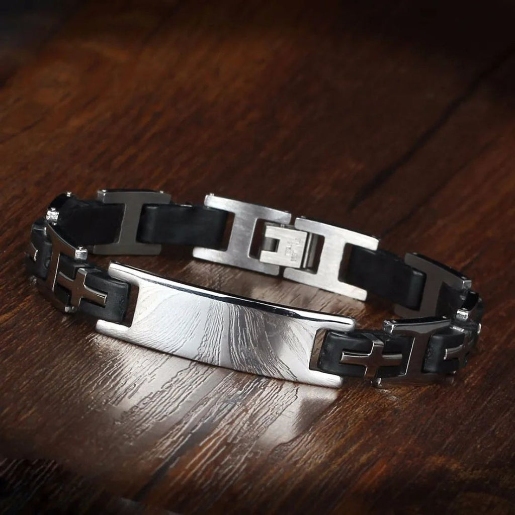 Pulsera personalizada con frase para hombre: brazalete de acero inoxidable y eslabones negros, placa rectangular plateada y diseño industrial. Ideal como regalo para hombre, presentada sobre superficie de madera pulida.