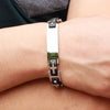Primer plano de una muñeca que lleva una Pulsera personalizada con frase para hombre, con placa rectangular plateada y diseño de eslabones de cadena negros y plateados: un regalo ideal para hombres.