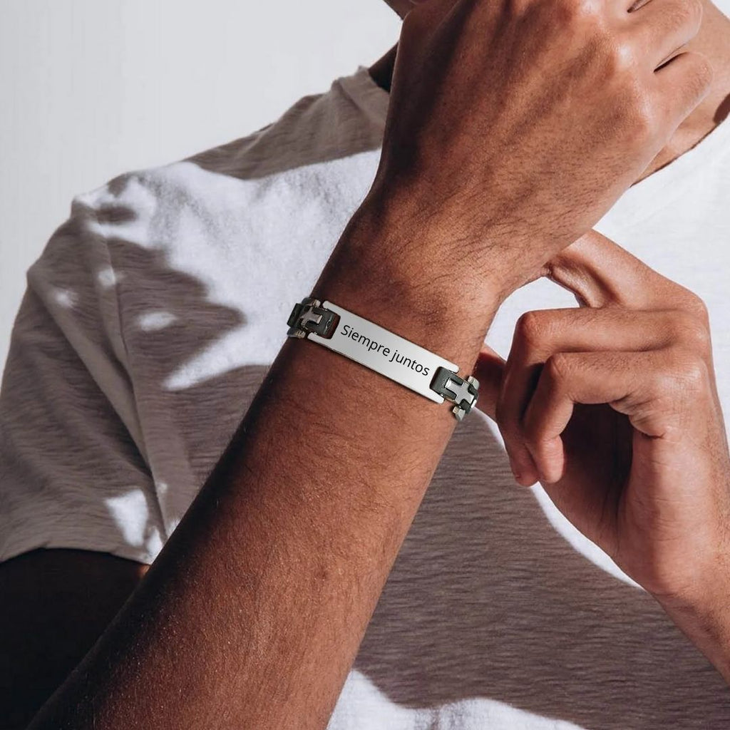 Una persona con camiseta blanca ajusta en su muñeca una Pulsera personalizada con frase para hombre, con una placa rectangular grabada con "Siempre Juntos", lo que la convierte en un regalo ideal para hombres.