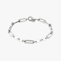 Pulsera personalizada con nombres en plata, con placas de nombre rectangulares con JOSE, LUCIA, HELEN y OSCAR grabadas uniformemente a su alrededor. Se muestra sobre fondo blanco: un regalo ideal para mamá.