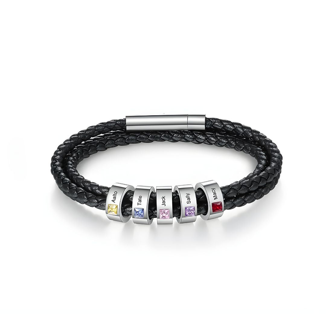 La Pulsera Piedras de vida - A mi Padre es una pulsera negra de cuero trenzado con seis cuentas de plata, cada una con piedra de nacimiento y nombre grabado. Un regalo ideal para el Día del Padre, rematada con un elegante broche plateado.