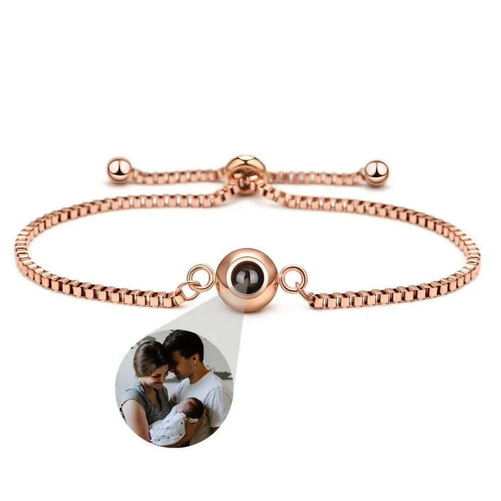 Pulsera Recuerdo eterno en oro rosa, ajustable, con un dije redondo que oculta una foto personalizada de una pareja con su bebé; detalle ampliado en la imagen. Un regalo memorable y personalizado.