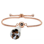 Pulsera Recuerdo eterno en oro rosa, ajustable, con un dije redondo que oculta una foto personalizada de una pareja con su bebé; detalle ampliado en la imagen. Un regalo memorable y personalizado.