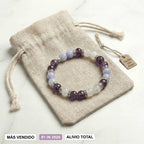 La Pulsera Serena - Alivio natural para la menopausia es una pulsera de piedritas moradas y celestes en bolsa beige con cordón, etiqueta "Hecho con Amor" y sellos: MÁS VENDIDO, #1 EN 2026, ALIVIO TOTAL para menopausia.