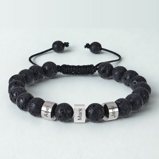 Pulsera tejida personalizada con nombres en color negro, ajustable, con tres cuentas rectangulares plateadas grabadas con "Abel", "Mark" y "Jeff". Pulsera para papá con cuentas texturizadas y porosas para un toque único.