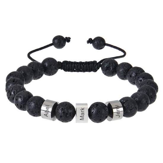 La Pulsera tejida personalizada con nombres es una pulsera de piedra volcánica negra con cordón ajustable y tres dijes plateados grabados con Apel, Mark y Jup, ideal como pulsera personalizada para papá.